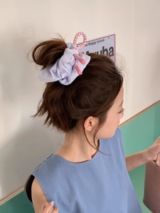 Close-up of a lilac scrunchie with pink checkered ring worn on a messy hair bun