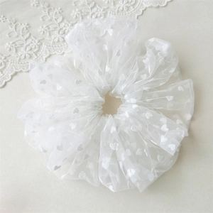 Detailed view of large white mesh scrunchie featuring elegant embroidered heart patterns