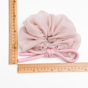 Pink mesh scrunchie with cylinder knot detail on white background and size rulers