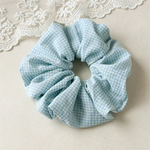 Detailaufnahme eines blau-weißen Gingham-Stoff-Haargummis mit feiner Nähtechnik