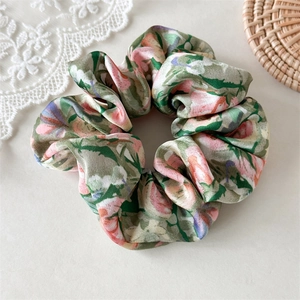 Detail eines Vintage-Haargummis mit Blumenmuster aus Satin in Pastellrosa und Lila