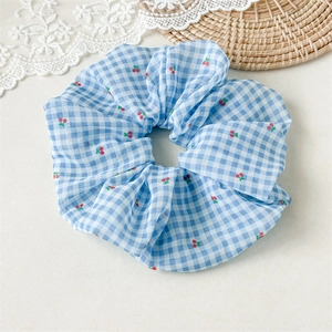 Détail de chouchou à carreaux bleu et blanc avec motif de cerises en tissu doux