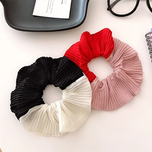 Close-up of pleated two-tone scrunchies in black-white and red-pink contrast fabric