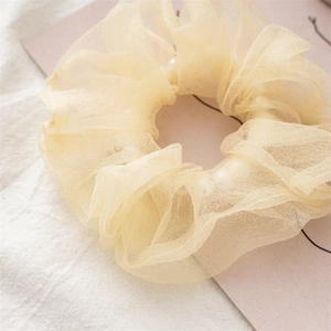 Détail d'un chouchou en organza champagne avec perles blanches et texture en tulle plissé