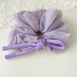 Detail of a purple organza scrunchie with layered fabric and satin drawstring detail