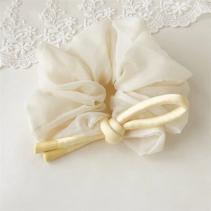 Detail of elegant yellow bow scrunchie made of chiffon and satin for hair styling