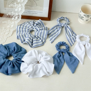 Close-up of blue striped scrunchies and bow hair ties set on a rustic beige table