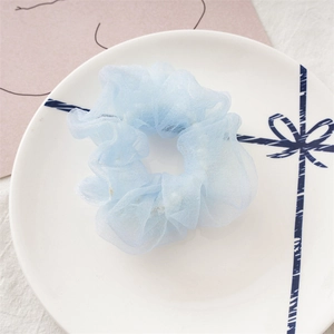 Détail d'un chouchou en organza bleu clair avec perles intégrées et plis doux
