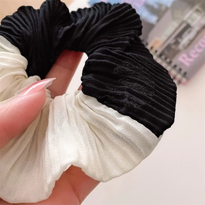 Macro shot of pleated fabric texture on a black and white contrast scrunchie accessory