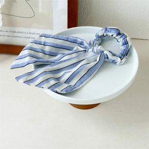 Blue and white striped scrunchie with long bow ribbon on a white ceramic stand
