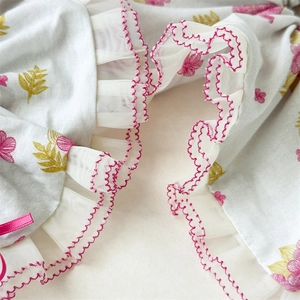 Détail de l'imprimé floral rose sur chouchou blanc avec dentelle et nœud satiné