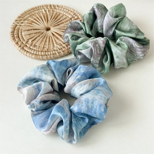 Detailed macro view of large satin scrunchies with elegant blue and green marble patterns