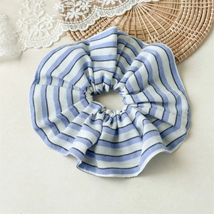 Detailed view of large blue and white striped fabric scrunchie on rustic lace background
