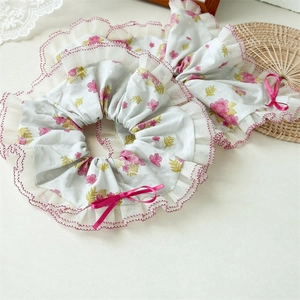 Détail de chouchous à fleurs bleu clair avec nœud en satin rose et bordure en dentelle