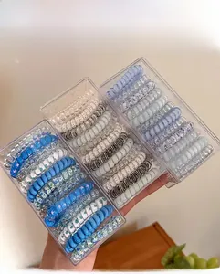 Detailed display of blue spiral hair ties in transparent storage boxes on wooden table