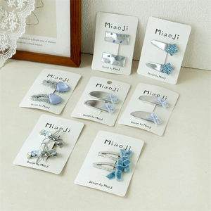Détail de pinces à cheveux en tissu bleu clair avec étoiles pailletées et nœuds velours