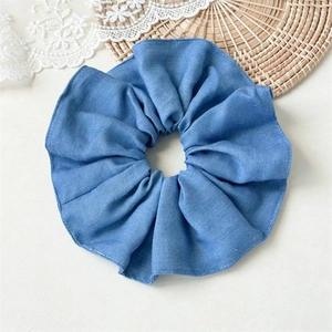 Detailed view of light blue striped denim scrunchie texture with neat stitching and ruffles