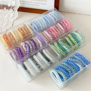 Detailed set of spiral hair ties in colorful options within clear storage boxes