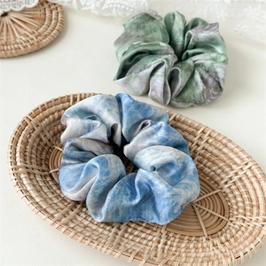 Close-up of elegant satin scrunchies with marble ink pattern in blue and green colors