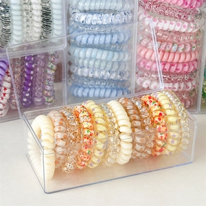 Close-up of spiral hair ties in various patterns stored in transparent acrylic boxes