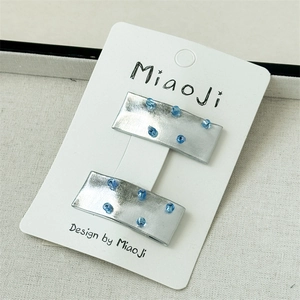 Vue détaillée de deux barrettes rectangulaires argentées avec perles bleues sur carte