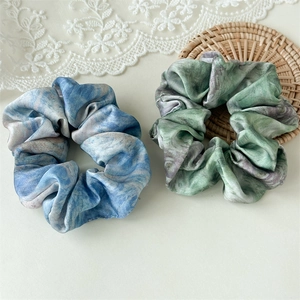Close-up of satin hair scrunchies with oil painting textures on a lace background