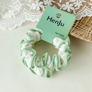 Détail d'un chouchou en coton blanc avec coutures ondulées vert clair et carte HenJu