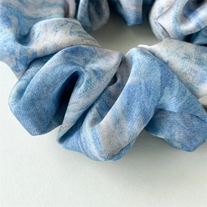 Macro shot of blue oil painting marble pattern satin scrunchie with smooth silk texture