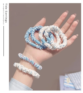 Gros plan de chouchous à fleurs bleu clair et blancs texturés à haute élasticité tenus en main