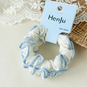 Détail d'un chouchou à fleurs blanches avec bordure ondulée bleue sur carte bleue