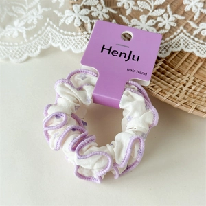 Chouchou fleuri avec bords plissés violets sur fond de dentelle blanche et rotin