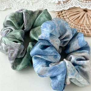 Detailed macro view of oil painting marble pattern satin scrunchies with elegant silk texture