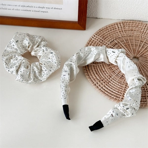 Close-up of cream pleated headband and scrunchie set with luxury rhinestones and silk gloss