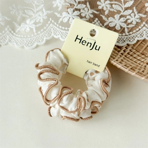 Détail d'un chouchou floral crème avec bords à volants marrons sur sa carte