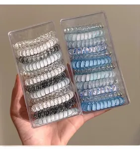 Close-up of seamless sea salt blue spiral telephone cord hair ties in clear packaging