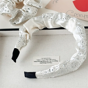 Detail of white satin headband and scrunchie set with luxury rhinestones on display