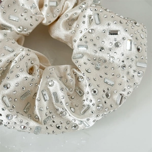 Macro shot of champagne satin scrunchie with sparkling round and baguette rhinestones