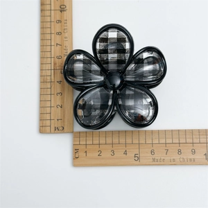 Dettaglio di un fermaglio per capelli a fiore scaccato di 5,5 cm su uno sfondo bianco