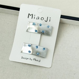 Détail de barrettes à cheveux en tissu étoile argentée avec strass bleus sur carte