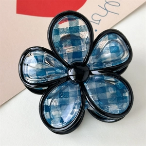 Dettaglio di un fermaglio per capelli a fiore con motivo a quadretti bianchi e blu