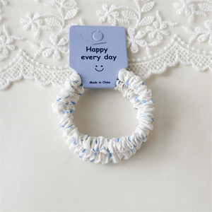 Gros plan d'un chouchou blanc à pois bleus avec une étiquette violette Happy every day
