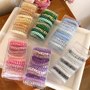 Colorful spiral phone cord hair ties set in clear boxes on a bright wooden table