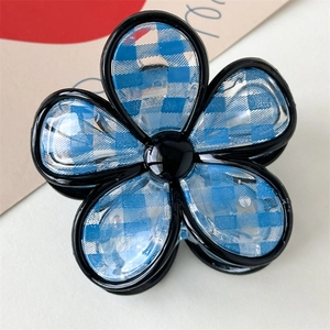 Dettaglio di un fermaglio per capelli a fiore con motivo a scacchi blu e bianchi e bordo nero