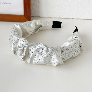 Detail of white satin headband with pleated knots and crystal rhinestones