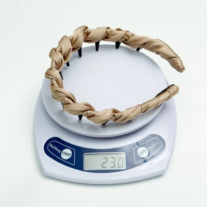Close-up of lightweight champagne satin headband showing 23g weight on a scale