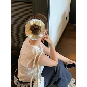 Dettaglio di un grande elastico floreale crema con bordo blu a balze su uno chignon