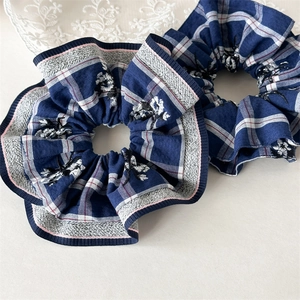 Close-up of blue and white checkered scrunchies with floral embroidery and pink piping