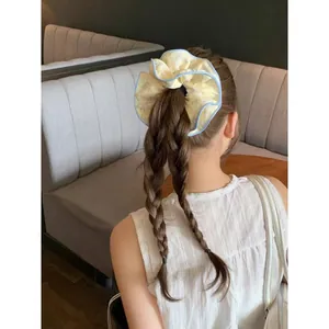 Dettaglio di un elastico per capelli con stampa floreale su capelli intrecciati moda