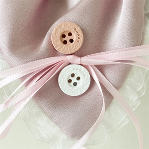 Detailed close-up of pink satin hair scrunchie with lace trim and Vogue buttons