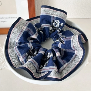 Detailed view of large blue plaid scrunchie with floral embroidery and pink stitching